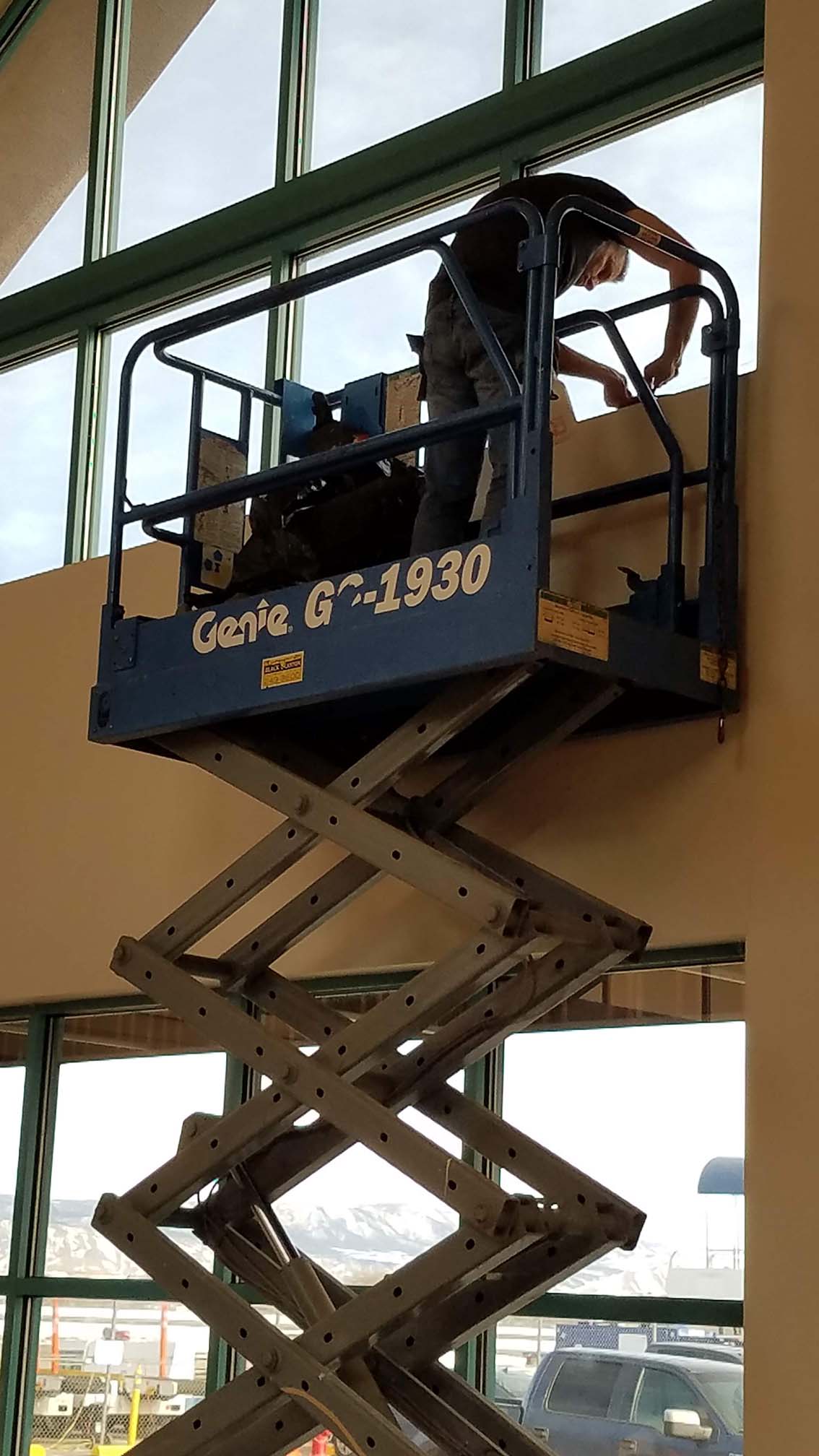 Expert technicians using a scissor lift for professional high-window tint installation